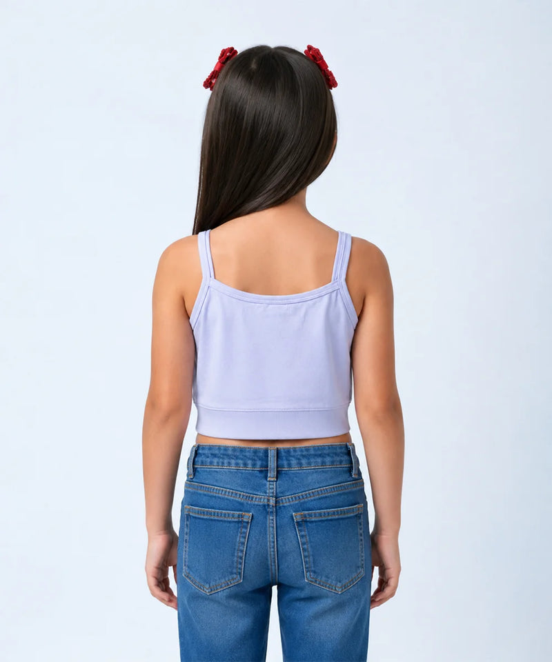 A young girl viewed from behind wearing a light lavender sleeveless crop top and blue jeans, with two red hair bows in her dark hair, against a light blue studio background.