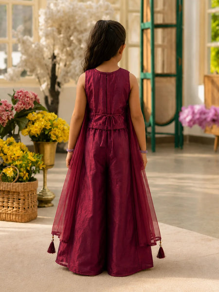 Young girl in a burgundy dress standing in a decorated room with flowers and furniture.