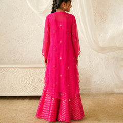 Person wearing a bright pink traditional outfit with a white textured wall in the background