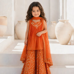 Young girl in an orange traditional outfit standing in a bright room with decorative vases.