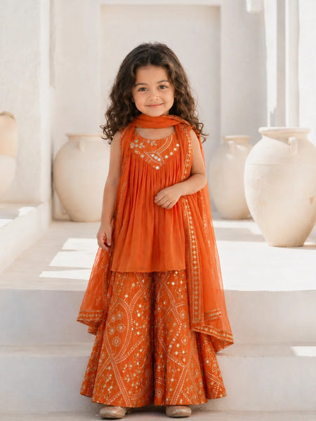 Young girl in an orange traditional outfit standing in a bright room with decorative vases.