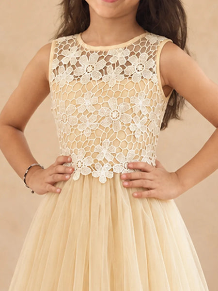A sleeveless young girl's dress with a cream floral lace bodice and a flowing champagne tulle skirt, shown on a model against a warm beige background.