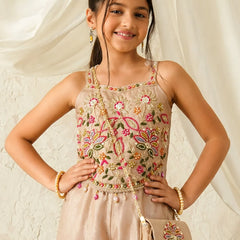 Young girl in a pink traditional outfit with a matching bag against a beige wall.