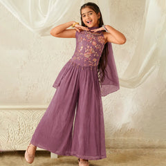 Young girl wearing a purple embroidered dress against a plain background