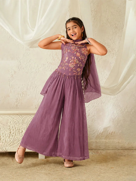 Young girl wearing a purple embroidered dress against a plain background