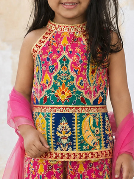 A young girl wearing a vibrant, multicolored traditional Indian embroidered top with a matching sheer pink dupatta, shown from the chest down against a light beige background.