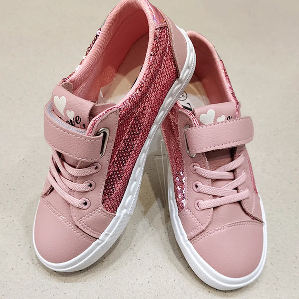 Pair of pink children's sneakers with white soles on a beige background