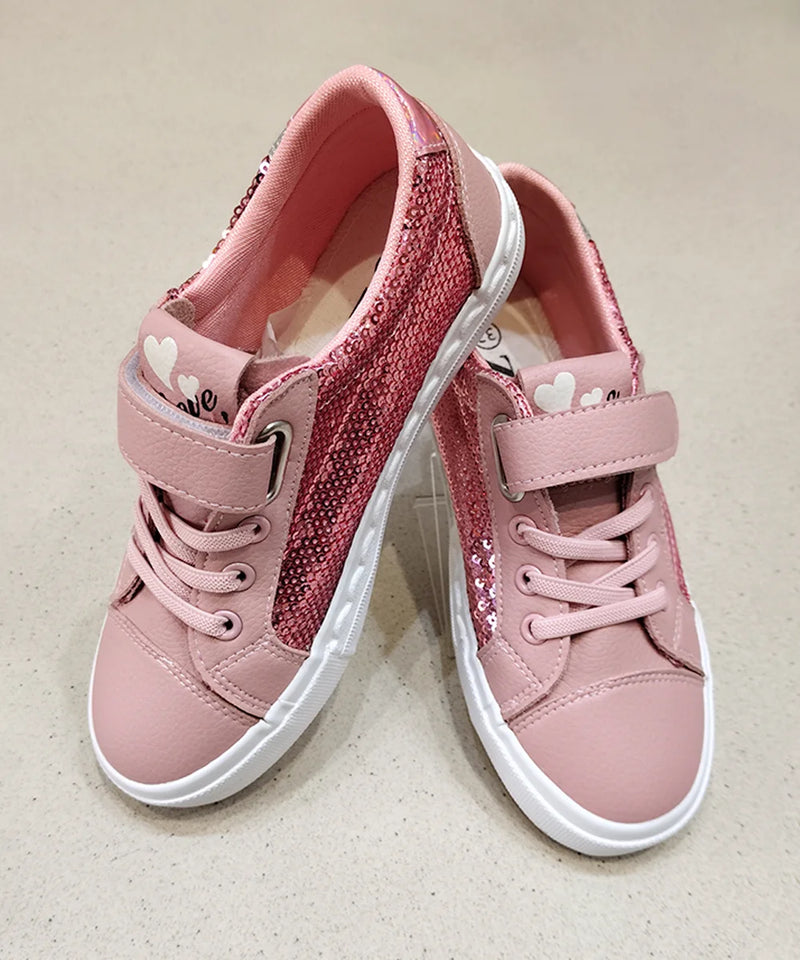 Pair of pink children's sneakers with white soles on a beige background