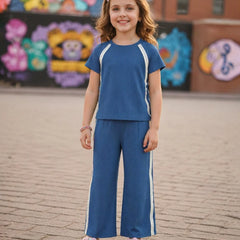 Young girl in a blue outfit standing on a brick pavement with colorful murals in the background
