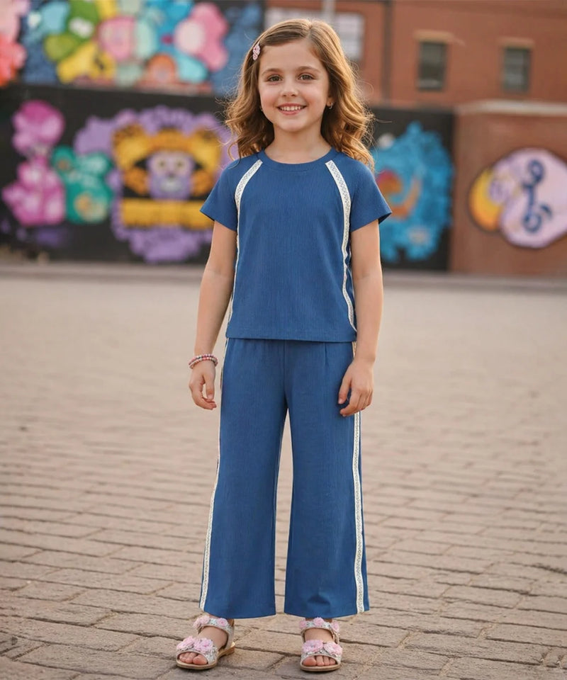 Young girl in a blue outfit standing on a brick pavement with colorful murals in the background