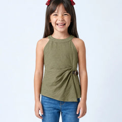 A young girl with dark hair and red bow clips is smiling, wearing an olive green sleeveless wrap-style top with blue jeans against a light gray studio background.