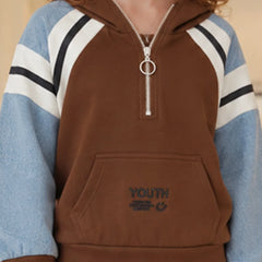 A person wearing a brown half-zip hoodie with light blue sleeves featuring white and black stripes, and a silver zipper pull with a ring detail. The front has a kangaroo pocket with 'YOUTH' embroidered on it.