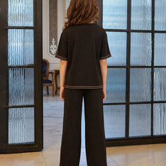 Young girl wearing a black outfit with a brand logo in the background

