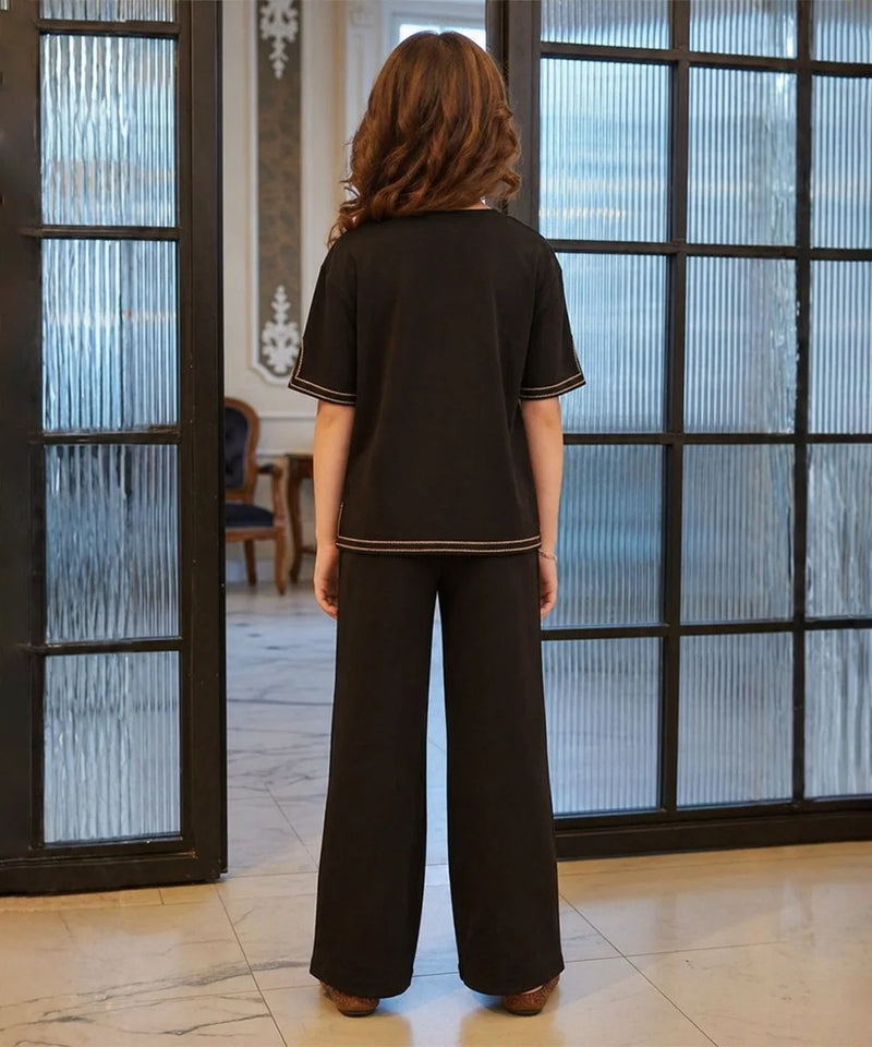 Young girl wearing a black outfit with a brand logo in the background

