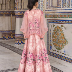 A woman viewed from behind wearing a pink floral traditional gown with sheer draped sleeves, standing in an ornate architectural hallway with decorative tiled walls.