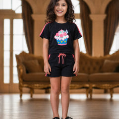 Young girl wearing a black outfit with a colorful design in a room with brown furniture.
