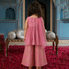Child in a pink dress standing in a decorated room with red carpet and blue walls.