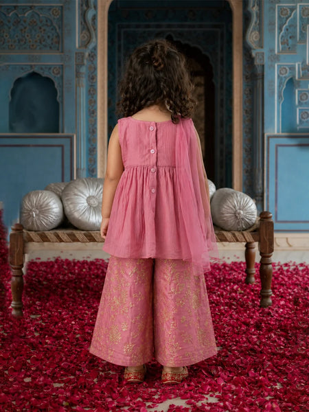 Child in a pink dress standing in a decorated room with red carpet and blue walls.