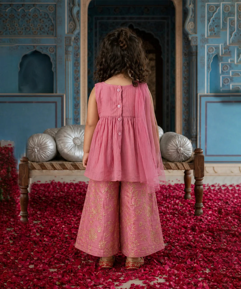 Child in a pink dress standing in a decorated room with red carpet and blue walls.