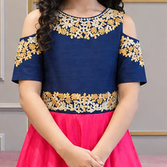 A child wearing a cold-shoulder navy blue top with gold and cream floral embroidery, paired with a bright pink skirt.
