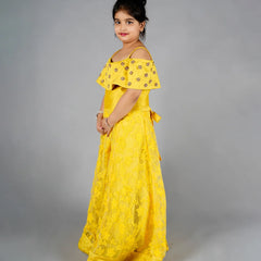 Young girl wearing a yellow dress with floral patterns on a gray background