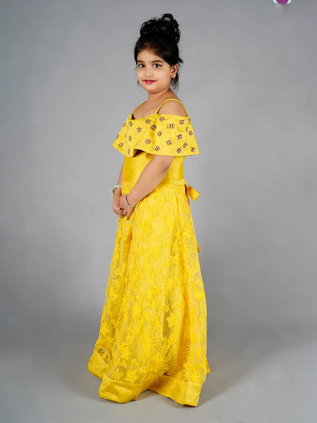 Young girl wearing a yellow dress with floral patterns on a gray background