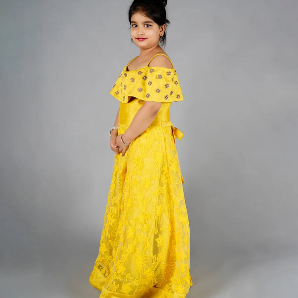 Young girl wearing a yellow dress with floral patterns on a gray background