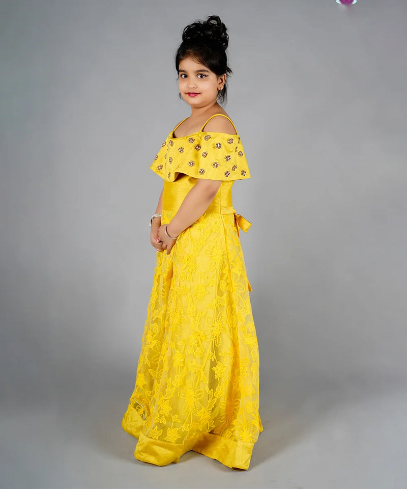 Young girl wearing a yellow dress with floral patterns on a gray background