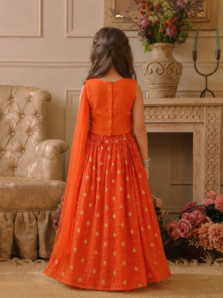 Woman in an orange dress standing in a room with decorative elements.