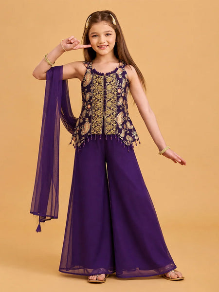 A young girl models a purple and gold traditional Indian outfit consisting of a sleeveless embroidered top with a matching sheer purple dupatta, set against a solid beige background.