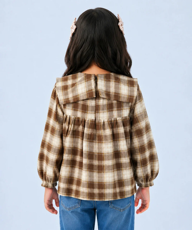 A child model shown from the back wearing a brown and beige plaid long-sleeve blouse with a wide collar and gathered back, paired with blue jeans against a light blue background.
