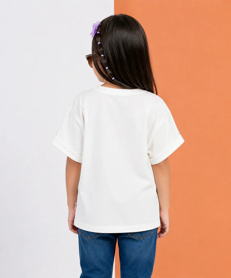 A child viewed from behind wearing an oversized white short-sleeve t-shirt and blue jeans, standing against a split white and orange background.