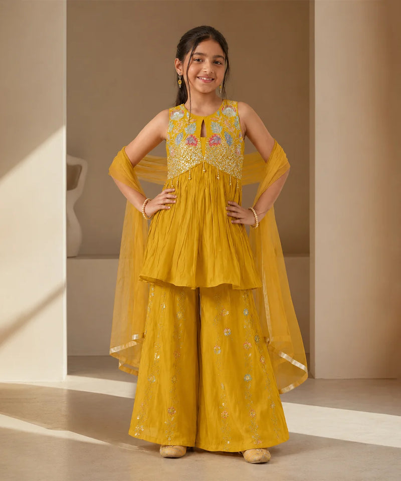 Girl wearing a mustard yellow embroidered sharara set with dupatta.