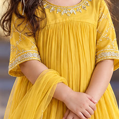 A close-up of a child wearing a bright yellow traditional dress with silver embroidered details around the neckline and sleeve cuffs, paired with a matching sheer dupatta.