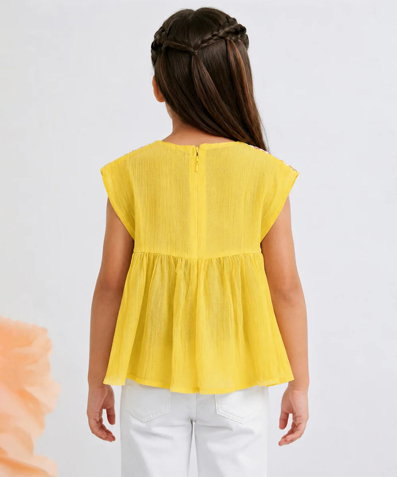 A child model shown from the back wearing a bright yellow sleeveless peplum top and white pants against a plain light gray background.