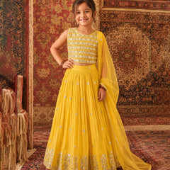 Young girl in a yellow traditional outfit standing on a patterned rug