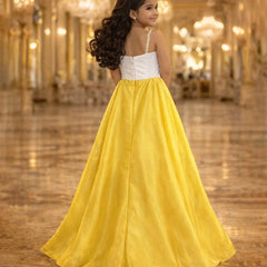 Woman in a white top and yellow skirt standing in a grand hall with chandeliers.