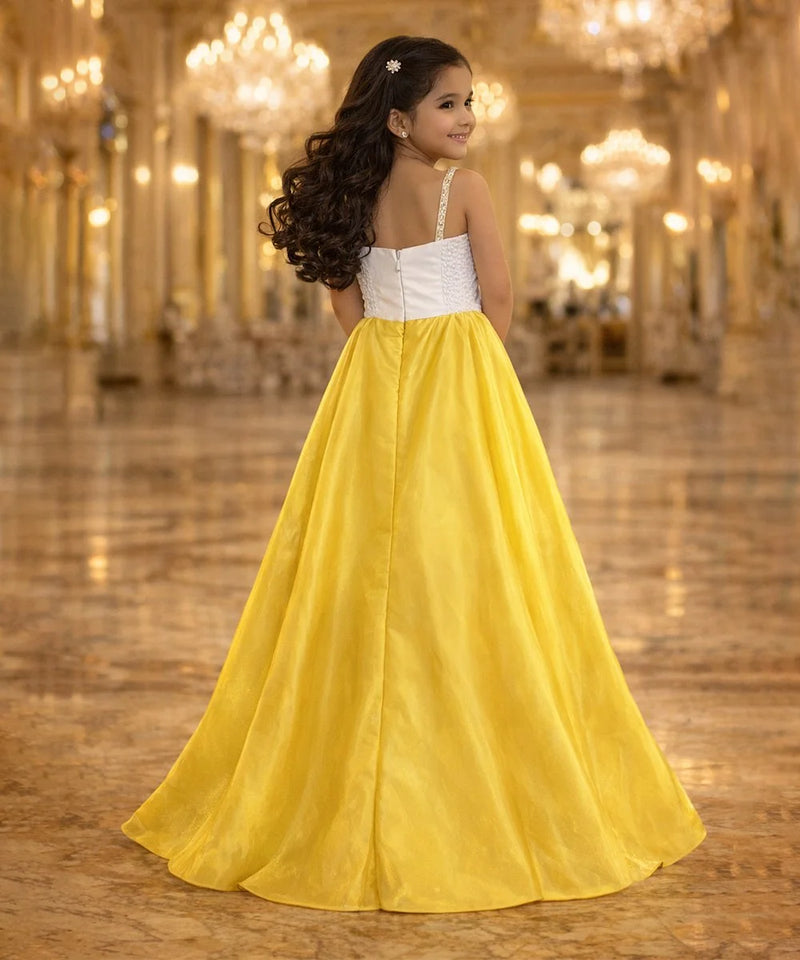Woman in a white top and yellow skirt standing in a grand hall with chandeliers.