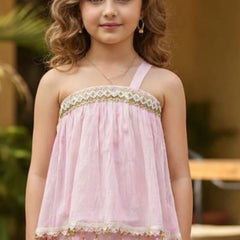 Young girl wearing a pink dress with gold accents outdoors.