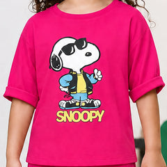 A child wearing a bright pink short-sleeve T-shirt with a large Snoopy graphic on the front. The graphic shows Snoopy wearing black sunglasses, a blue jacket, a yellow shirt, and blue jeans, with the word 'SNOOPY' printed below in yellow.
