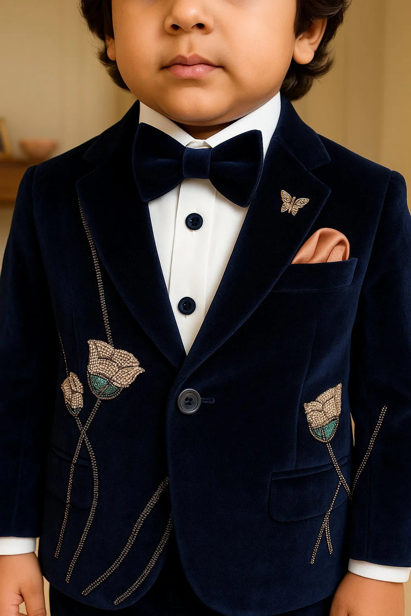 Child wearing a navy velvet suit with butterfly details and a bow tie.