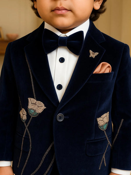 Child wearing a navy velvet suit with butterfly details and a bow tie.
