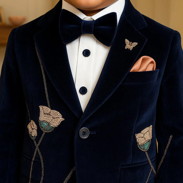 Child wearing a navy velvet suit with butterfly details and a bow tie.