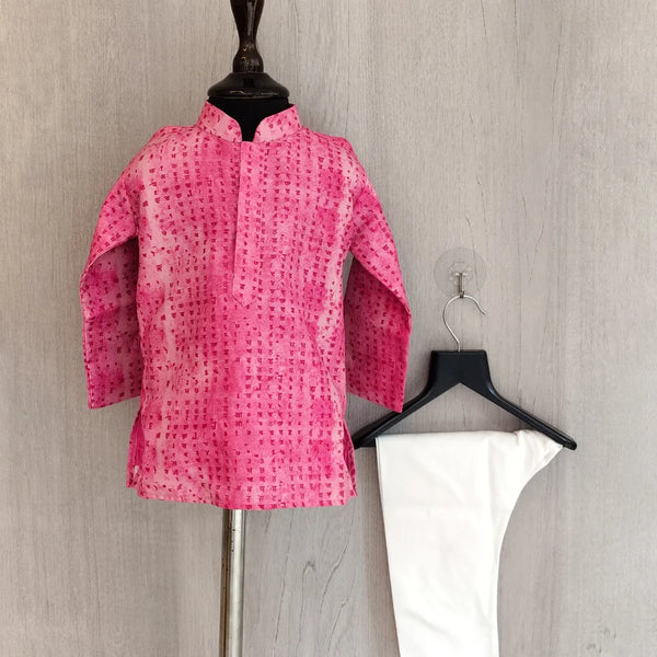 Pink patterned shirt on a mannequin and white pants on a hanger against a gray background