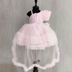 A beige knee-length party frock for girls, featuring a floral and time print, a round neck, sleeveless design, and a neon pink colored bow with an attached belt on the front.