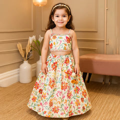 Young girl in a floral dress standing in a room with beige walls and a vase with flowers.