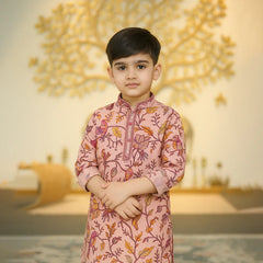 Young boy wearing a pink traditional outfit with floral patterns in a decorated indoor setting.
