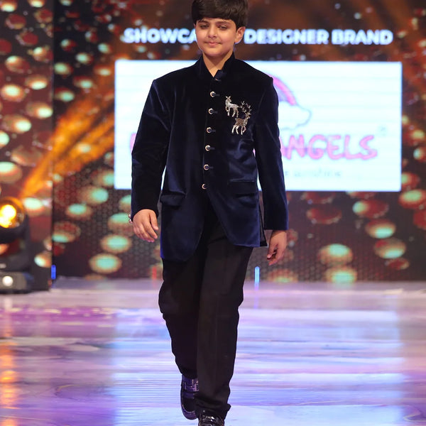 Child model walking on a ramp wearing a blue jodhpuri velvet suit