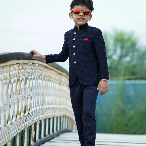 It's a navy blue Colored self-Jacquard design Jodhpuri Suit for Boys. It consists of a Jodhpuri Coat along with matching pants and a red coloured pocket square.