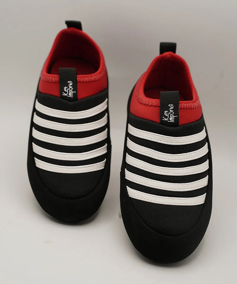 Kids' black slip-on sneakers with bold white stripes and red collar, Jaipur
